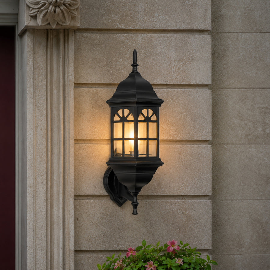 Black metal outdoor wall light lifestyle image with arched paneled glass shade mounted on an elegant stone column.