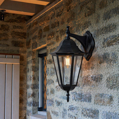 Black metal outdoor lantern wall light lifestyle image beside rustic brick wall for elegant exterior decor.