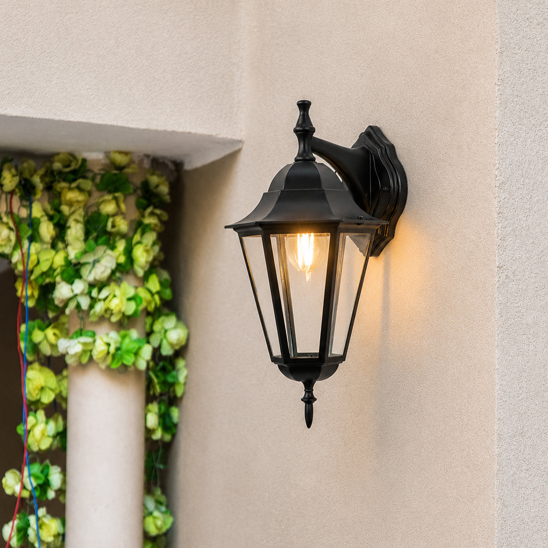 Black metal outdoor lantern wall light lifestyle image with warm glow for stylish exterior entryway decor.