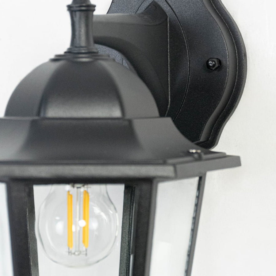 Closeup of classic outdoor wall lantern showing refined black metal detailing and transparent glass panes for clear brightness.