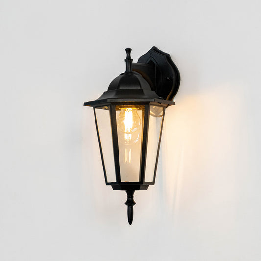 Black metal outdoor wall light on white background with clear glass shade for classic exterior decor.