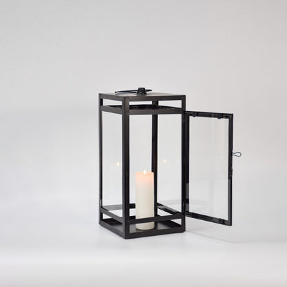 Black metal lantern displayed on white background featuring glass panels open door design and classic decorative lighting appeal.
