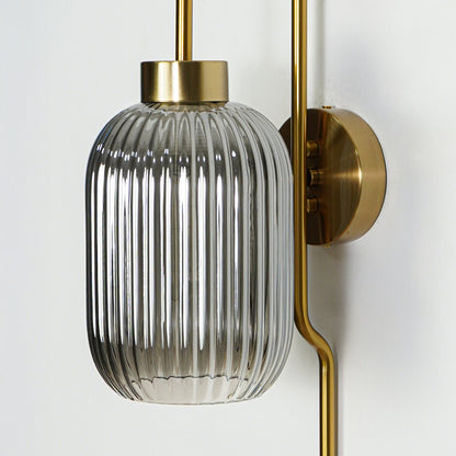 Closeup of gold metal wall light with ribbed glass shade showcasing detailed texture and premium finish for modern decor styling.