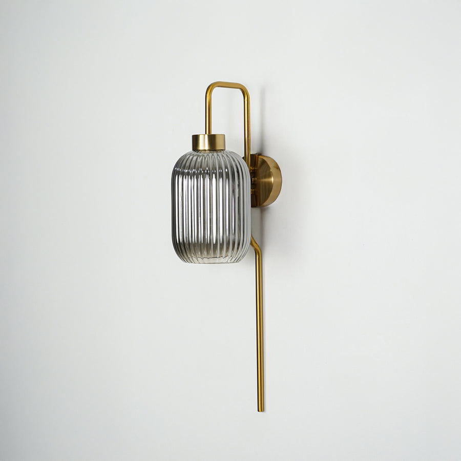 Gold finish wall light with smoked ribbed glass shade perfect for elegant interior wall decor placement on clean background.