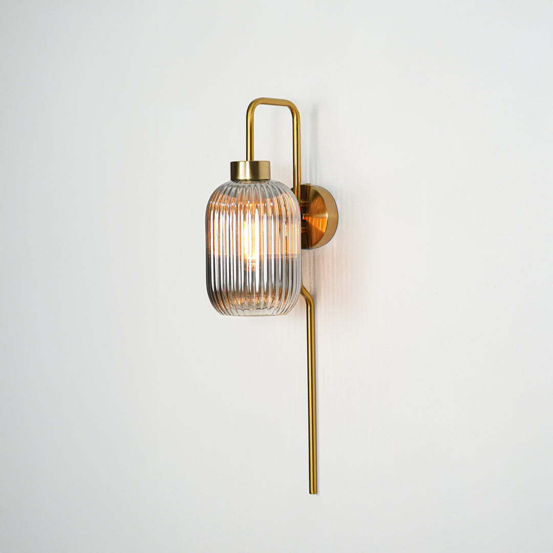 Gold metal wall light with ribbed glass shade and vertical rod design ideal for modern bedroom or hallway wall decor.