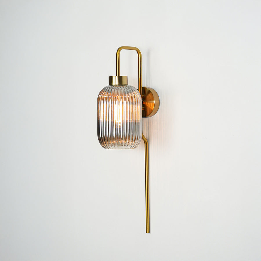 Gold metal wall light with ribbed glass shade and vertical rod design ideal for modern bedroom or hallway wall decor.