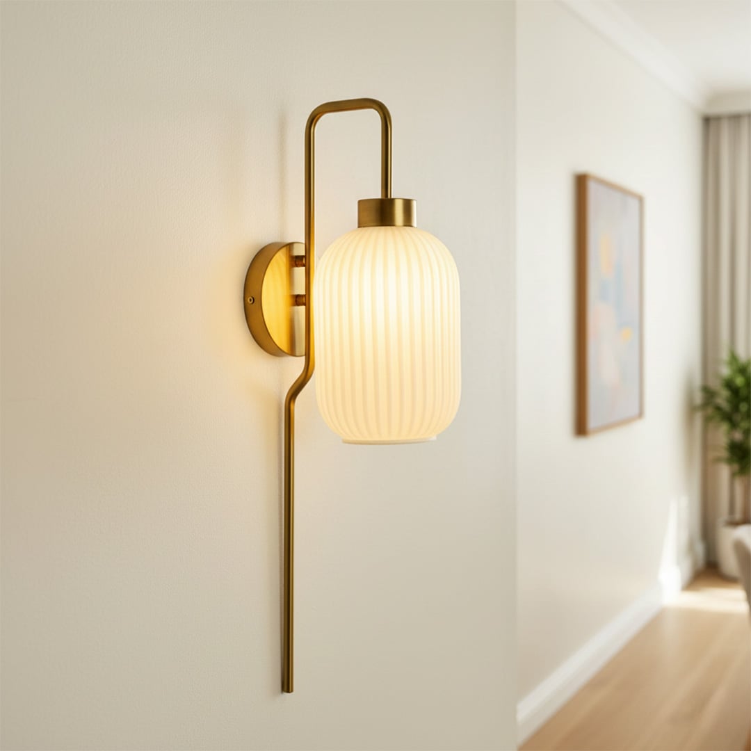 Modern gold wall sconce with ribbed frosted glass shade illuminating hallway wall with warm ambient lighting decor.