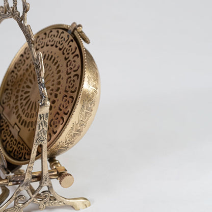 A closeup view of the brass swing bowl highlights the engraved floral patterns the curved lid handle and the detailed carved frame showcasing fine craftsmanship.