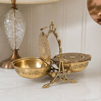 Antique gold metal decorative box with ornate lid placed on a tabletop adding vintage elegance and charm.