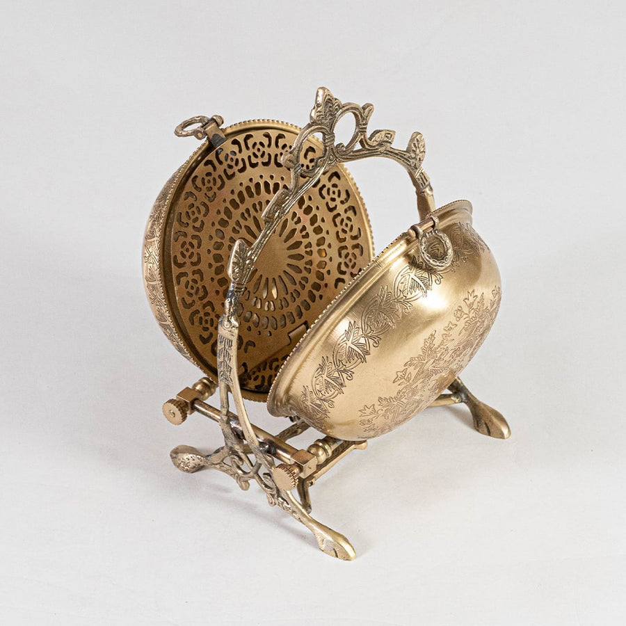 A decorative brass bowl with engraved artwork is captured on a white background emphasizing its curved shape and vintage metal craftsmanship.