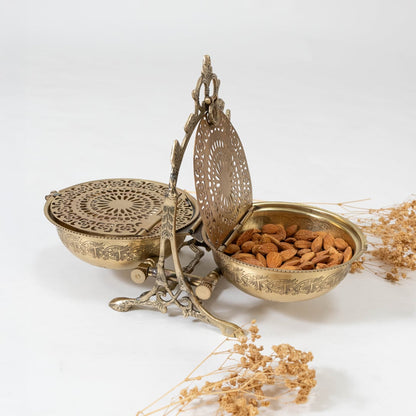 A brass swing serving bowl with carved patterns shown on a clean white background highlighting its engraved lid stand and vintage inspired ornamental frame.