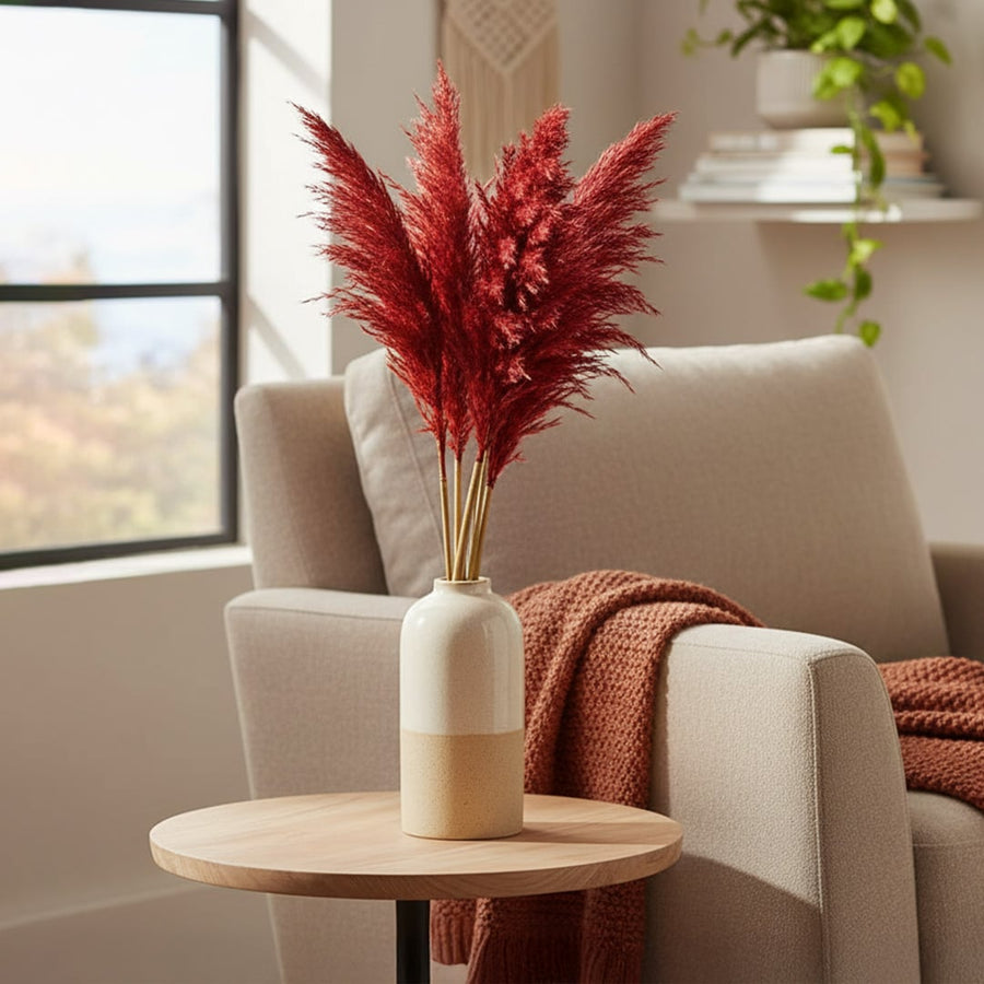 Decorative dried flower arrangement in ceramic vase placed on side table adding warm natural accent to cozy living room decor.