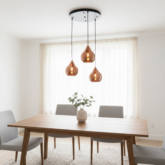 Modern copper metal pendant light trio with glossy teardrop shades adding warm contemporary style to dining or living room interiors.