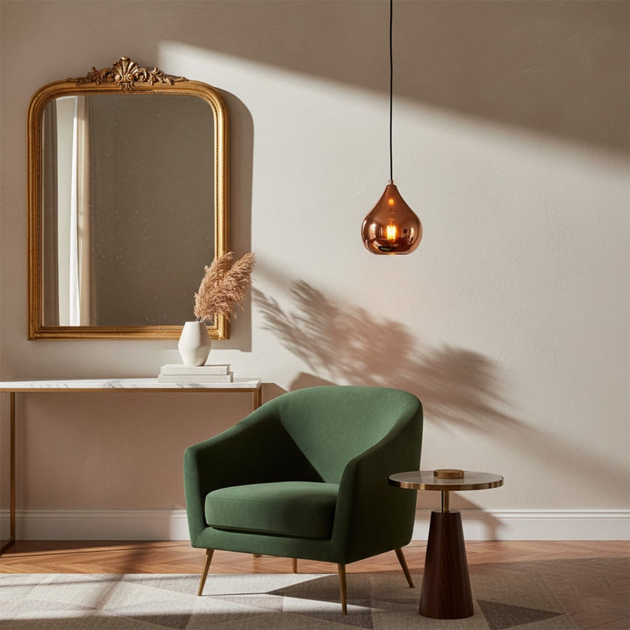 Copper metal pendant light with teardrop shape styled in modern interior creating warm reflective ceiling lighting ambiance.