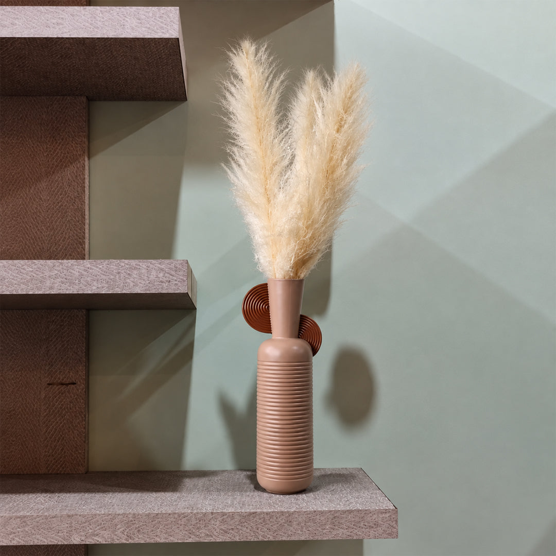 A ribbed terracotta ceramic vase with a matching round lid, holding dried pampas grass, styled on a textured stone shelf against a sage green wall.