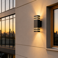 Modern black metal rectangular grid up down exterior wall sconce light on beige stucco facade for contemporary balcony.