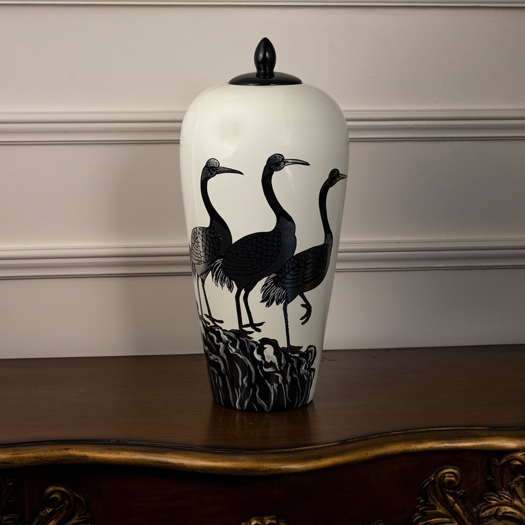 Round ceramic jar on plain white background with gold lid and base featuring delicate blossom and butterfly painting.