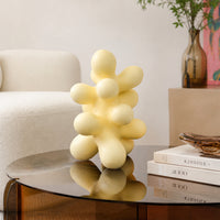 Yellow abstract ceramic sculpture placed on glass table for stylish modern living room decor styling.