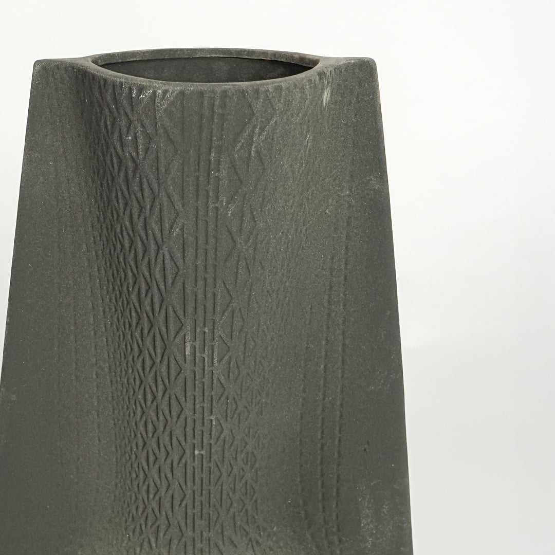 Close up view black textured ceramic vase showing carved surface matte finish decorative ceramic accent for modern home styling.