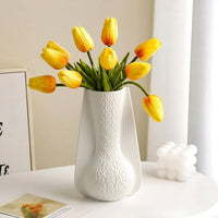 White ceramic decorative vase styled with yellow tulips creating an elegant focal point in modern home decor.