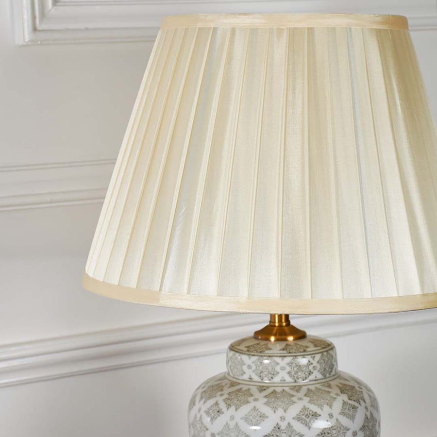 Closeup of the ceramic table lamp highlighting its intricate grey lattice pattern and smooth finish beneath the pleated shade.