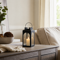 Modern black metal candle lantern with clear glass panels adding cozy ambient lighting to contemporary living room decor.