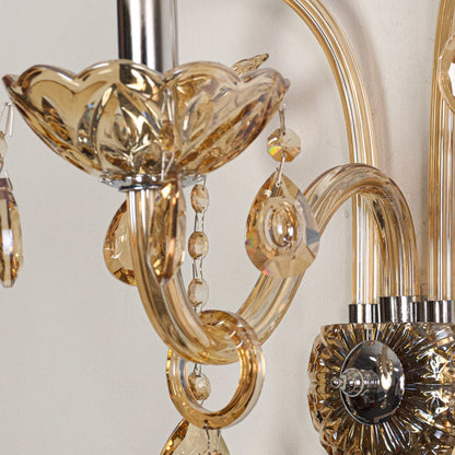 Closeup of champagne wall light showing curved glass arms and crystal drops for refined elegant interior lighting.