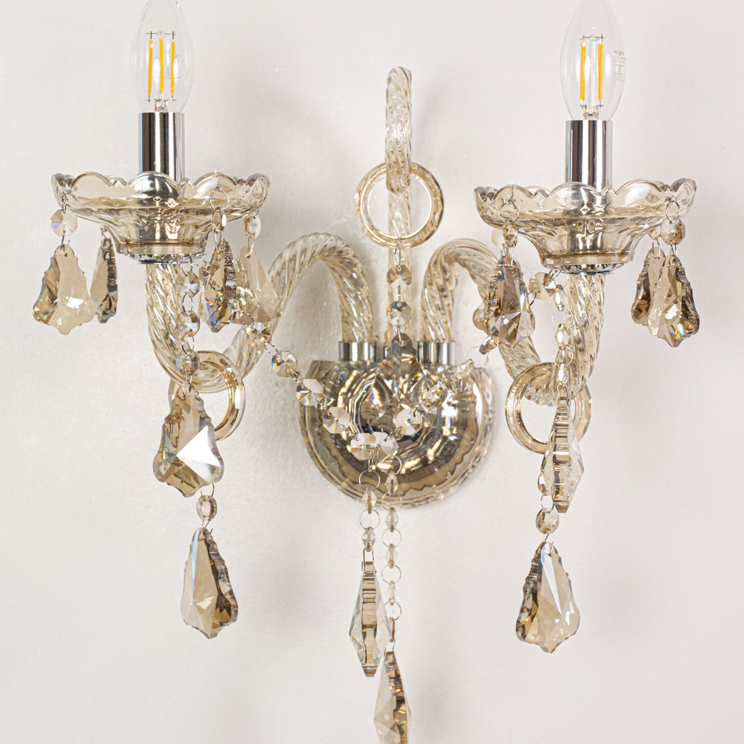 Closeup of champagne wall light showing twisted glass arms and crystal drops for refined elegant interior lighting.
