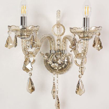 Closeup of champagne wall light showing twisted glass arms and crystal drops for refined elegant interior lighting.