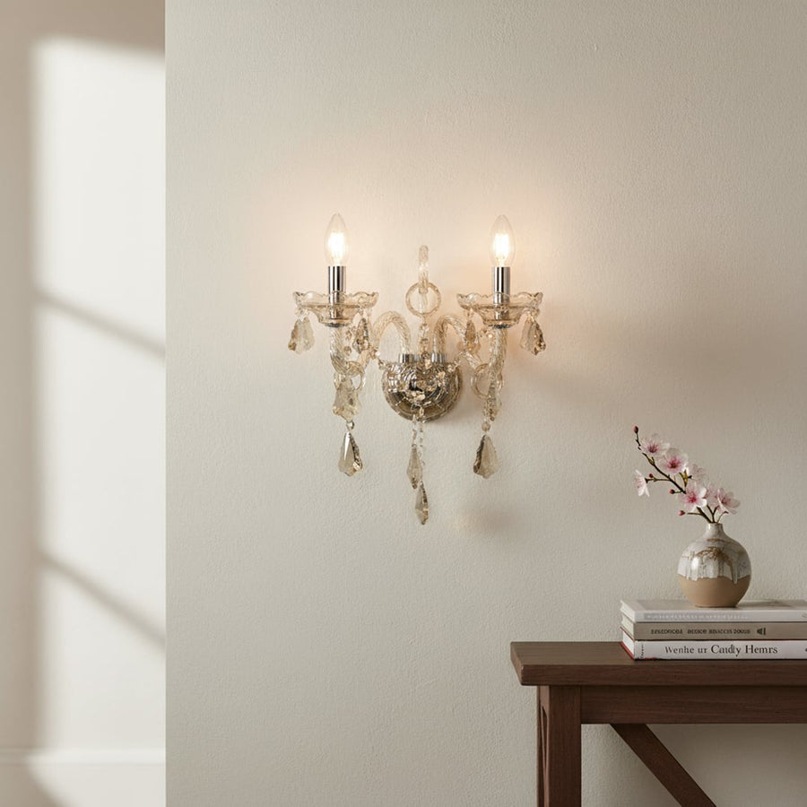 Wall light with champagne glass frame and crystal droplets styled on a soft wall background for elegant warm home lighting.