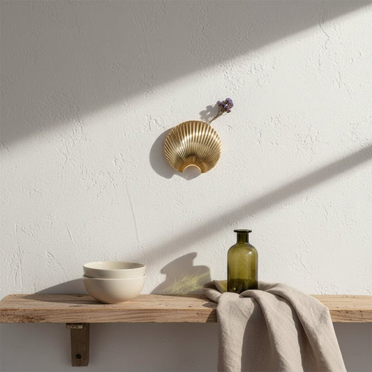 A gold shell decor piece displayed on a clean wall setting offering a modern and elegant lifestyle look with a soft minimal aesthetic.