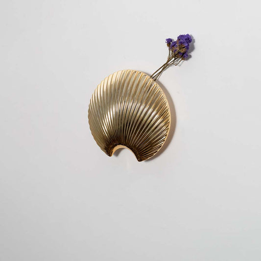 Gold finish metal leaf wall hook styled on a modern wall for bedroom entryway or living room decor and storage.