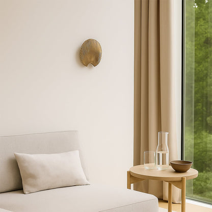 A gold decorative shell piece displayed on a clean wall creating a minimal lifestyle look with soft shadows and a modern sculptural feel that enhances elegant home styling.