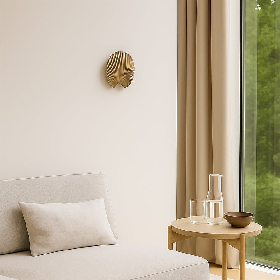 A gold decorative shell piece displayed on a clean wall creating a minimal lifestyle look with soft shadows and a modern sculptural feel that enhances elegant home styling.