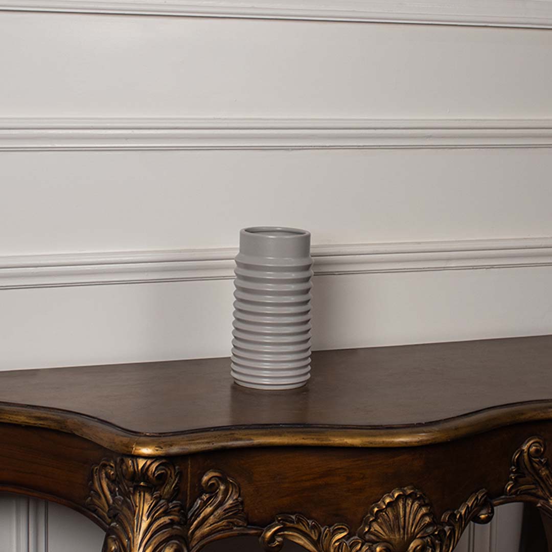 White ribbed ceramic vase styled on a vintage wooden console table adding elegant texture to classic home decor settings.