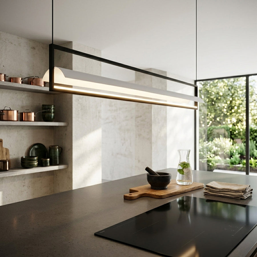 Modern linear pendant light with slim metal bar installed above kitchen island in contemporary kitchen with window and natural light.