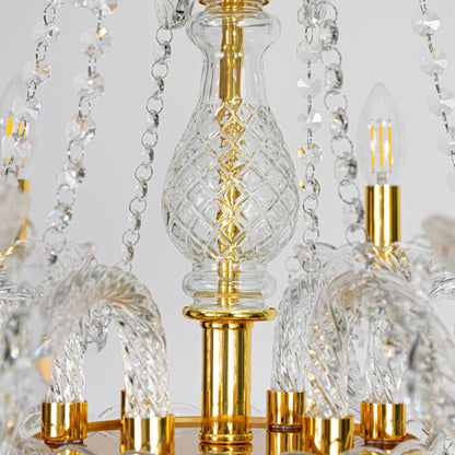 Closeup of gold metal crystal chandelier with crystal droplets and carved arms perfect for luxury interior ceiling decor.