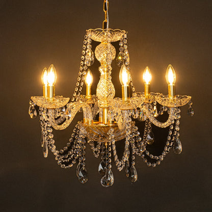Gold metal crystal chandelier glowing warmly on black background creating a dramatic luxury ceiling feature.