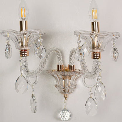 Closeup of clear crystal wall light with gold finishes and crystal drops perfect for luxury interior wall decor.