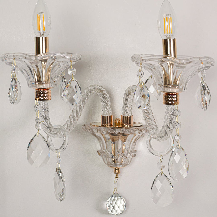 Closeup of clear crystal wall light with gold finishes and crystal drops perfect for luxury interior wall decor.