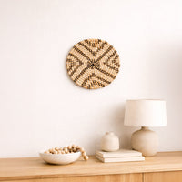 Natural woven wall basket displayed above a bedside table for artistic bohemian wall decor and cozy home interiors.