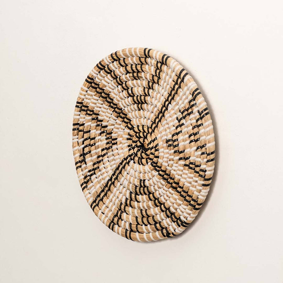 Side view of handcrafted black and natural seagrass wall basket with geometric chevron star pattern for boho wall decor.