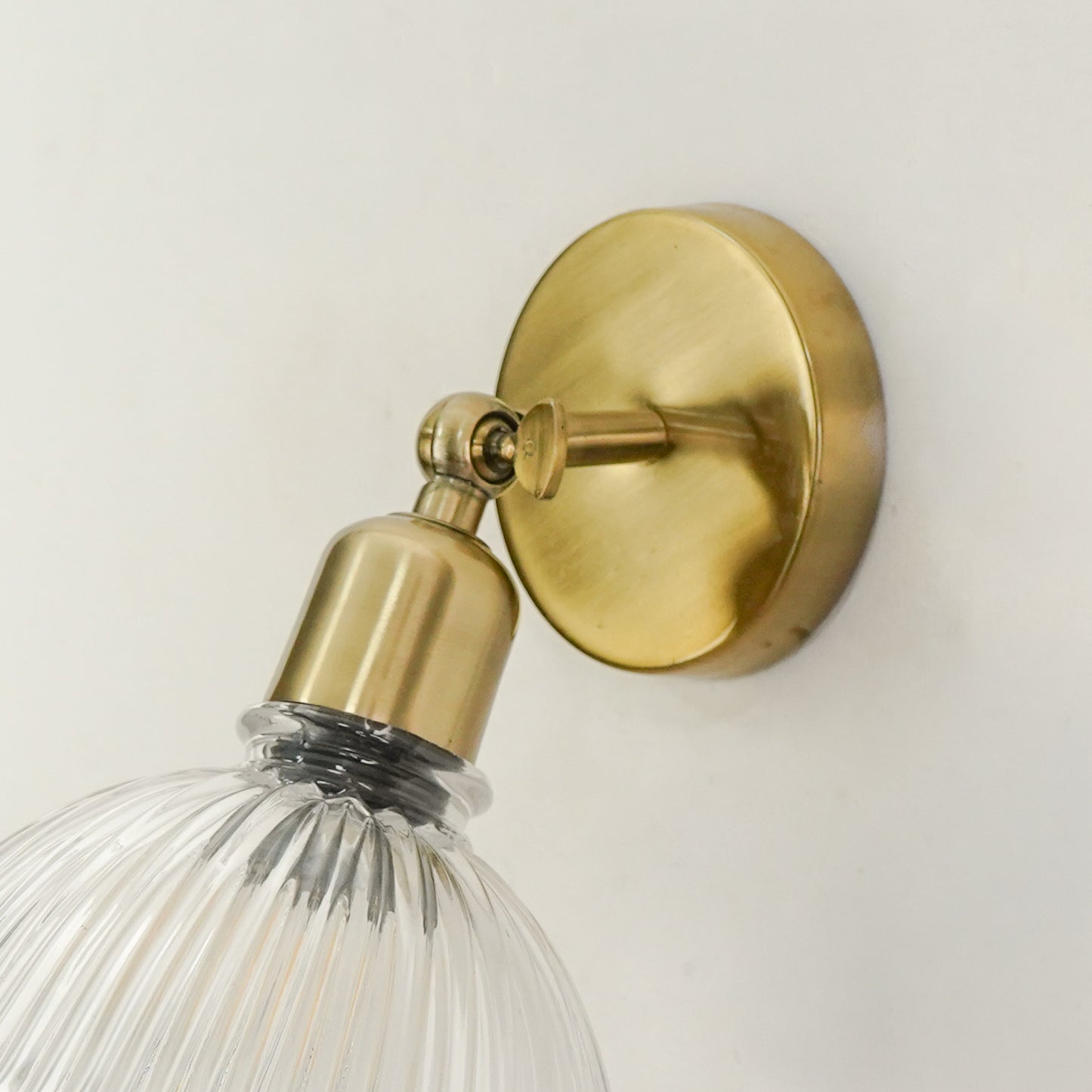 Closeup image of elegant ivory half shade wall sconce with antique brass finish for modern home interior lighting design.