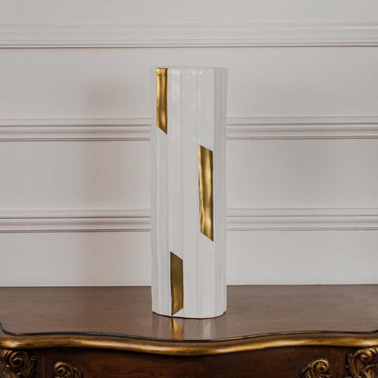White faceted ceramic cylinder vase with gold geometric accents displayed on a vintage wood console table for luxury styling.