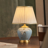 Blue ceramic table lamp with white fabric shade for bedroom bedside table and cozy living room ambient lighting.