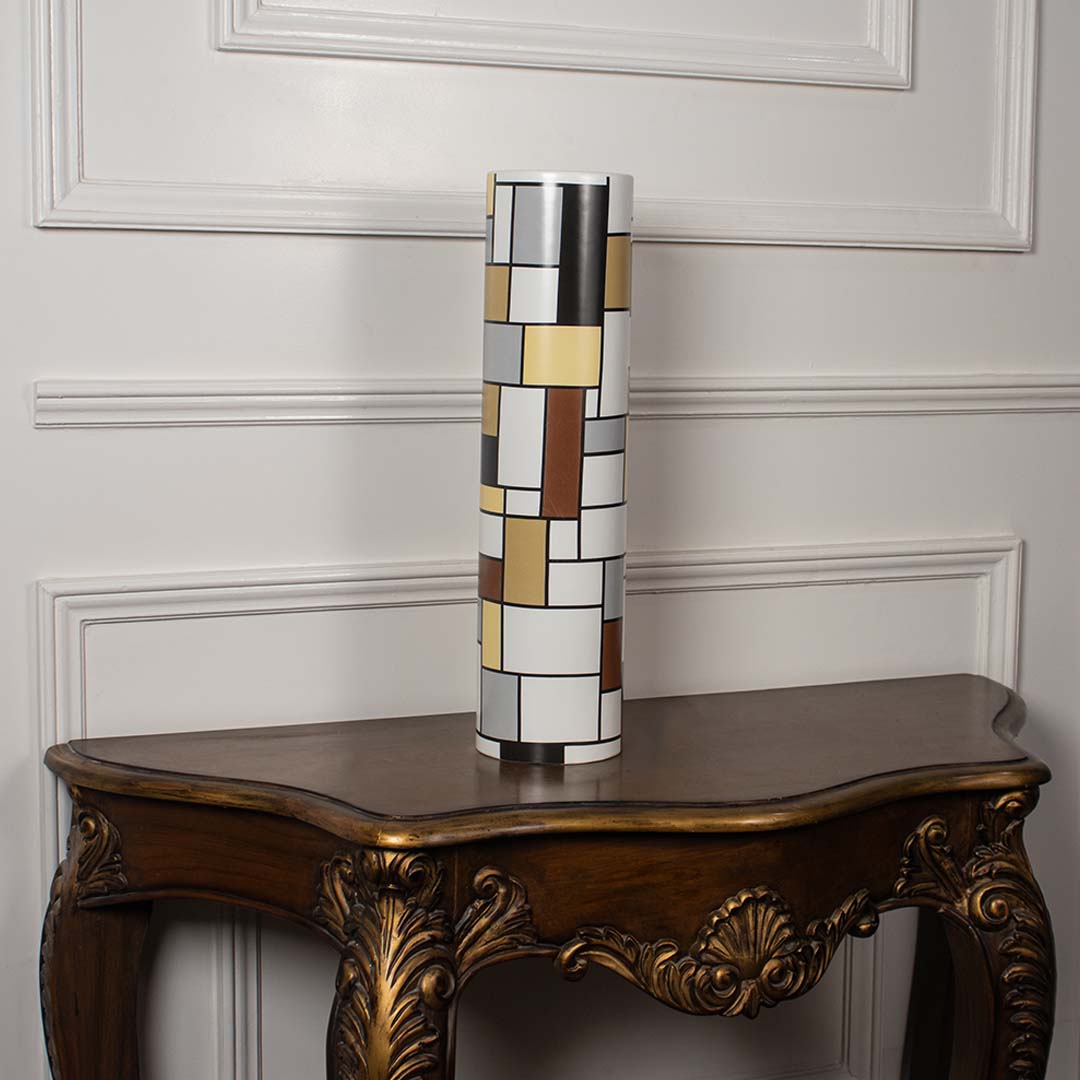 Tall ceramic cylinder vase featuring a geometric block grid pattern displayed on a vintage wood console table for home decor.
