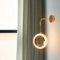 Modern rose gold led ring wall sconce lighting fixture glowing on wall in luxury living room setting for home interior.