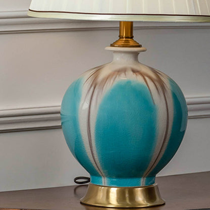 Closeup of turquoise ceramic table lamp with pleated white shade and gold detailing showing elegant finish for modern home decor lighting.