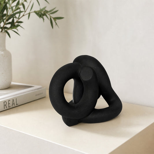 Black abstract ceramic sculpture placed on modern shelf with books for elegant contemporary home decor styling.