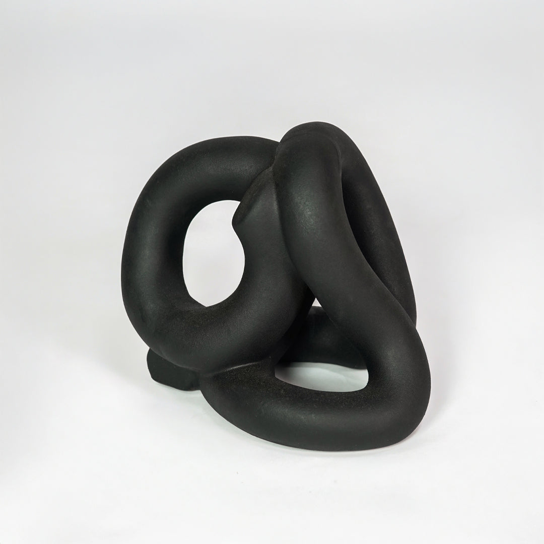 Black abstract ceramic sculpture on white background for elegant contemporary home decor styling.